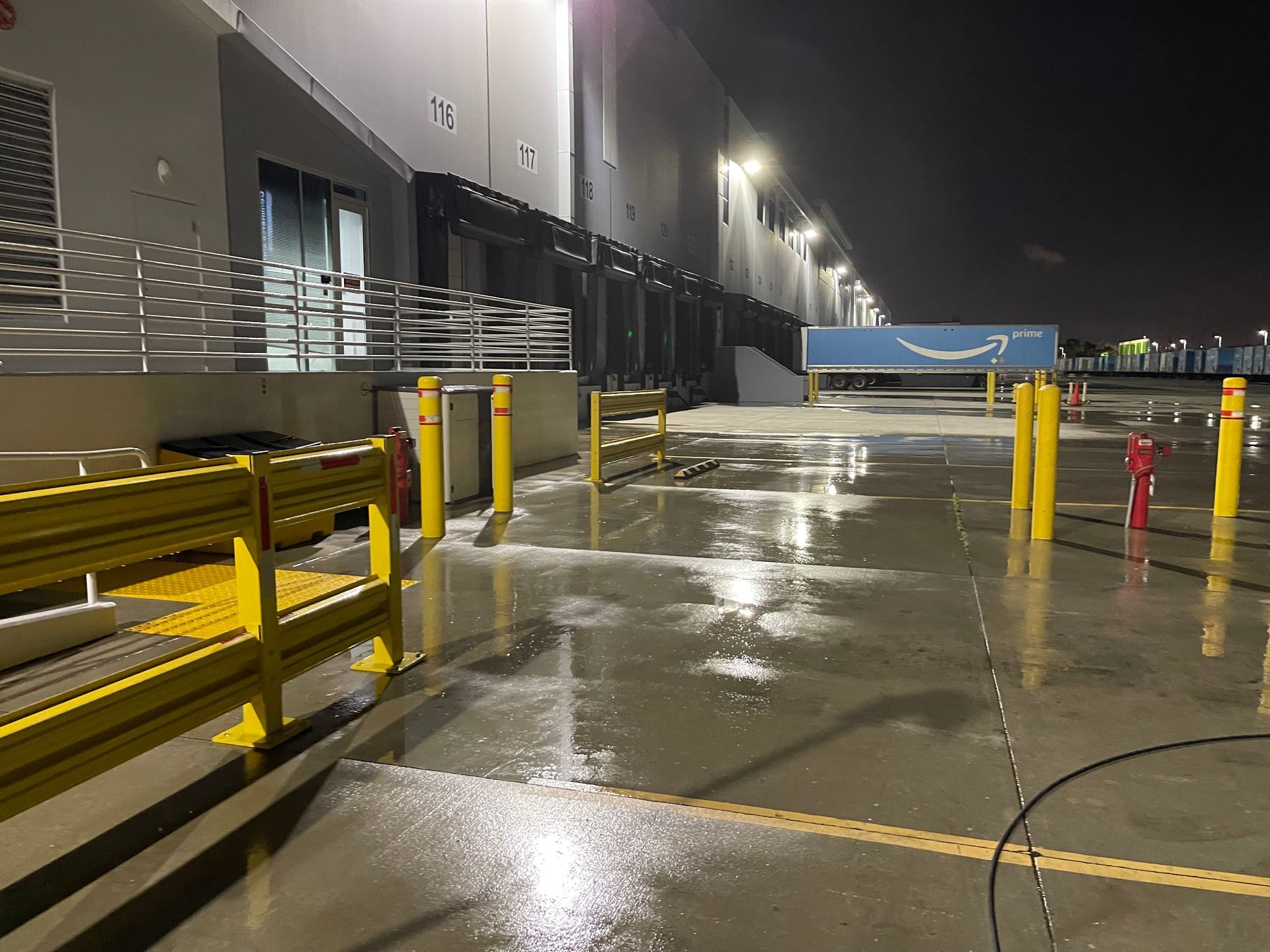A warehouse is being cleaned at night with a fire hydrant in the foreground.
