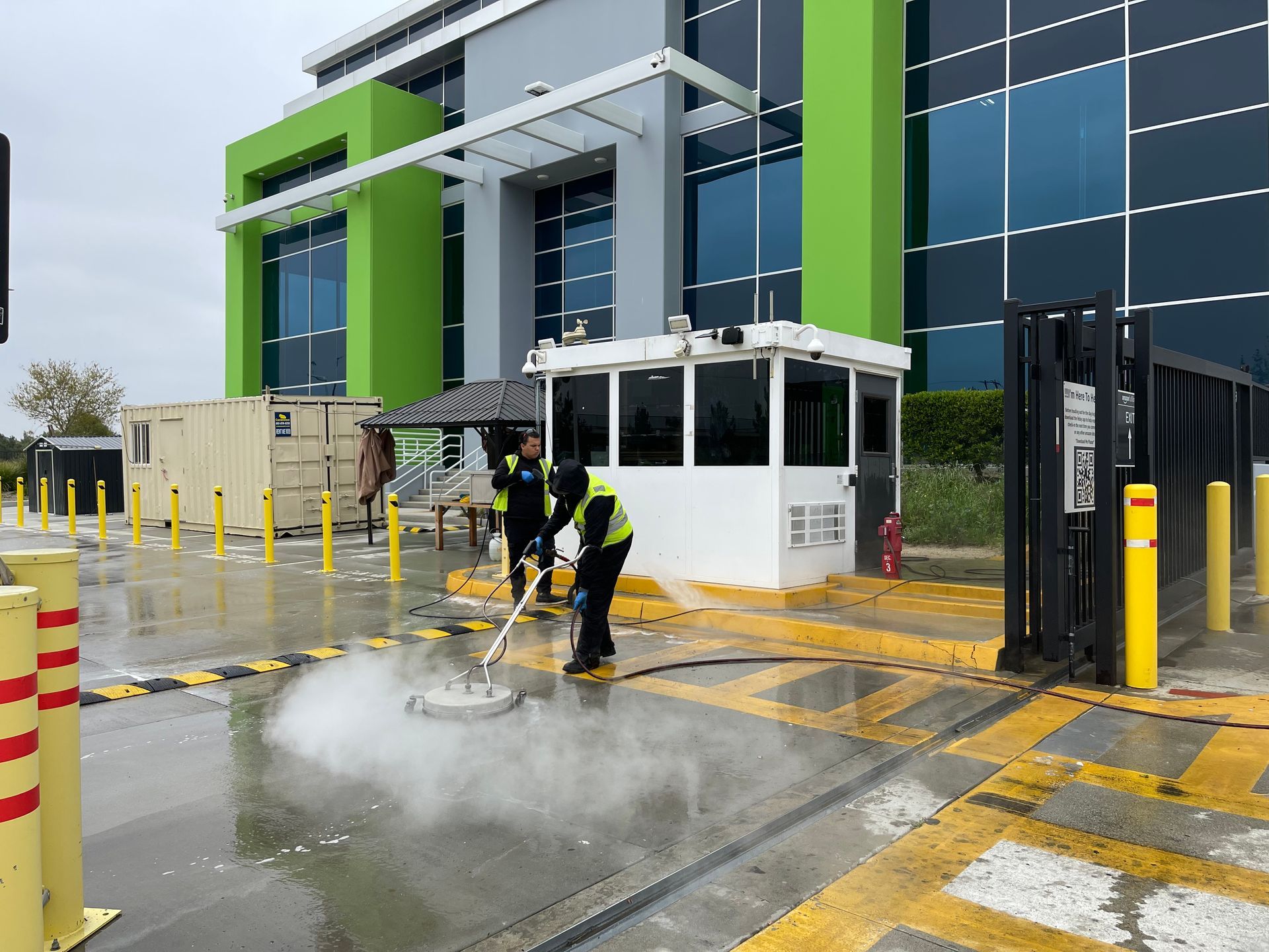 A group of people are cleaning a parking lot in front of a building.