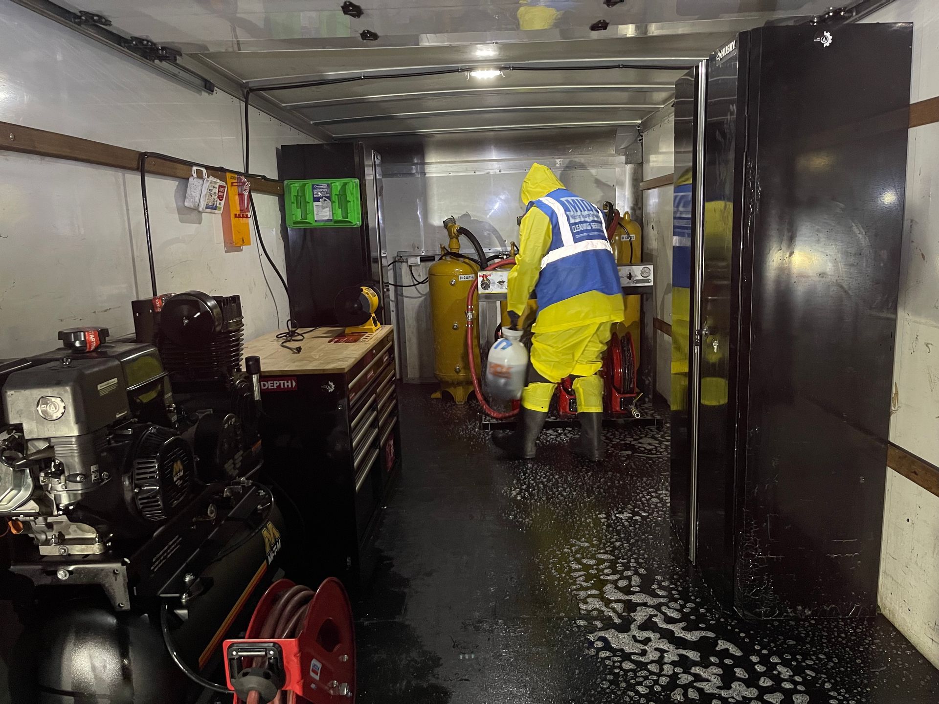 A man in a yellow vest is standing inside of a trailer.
