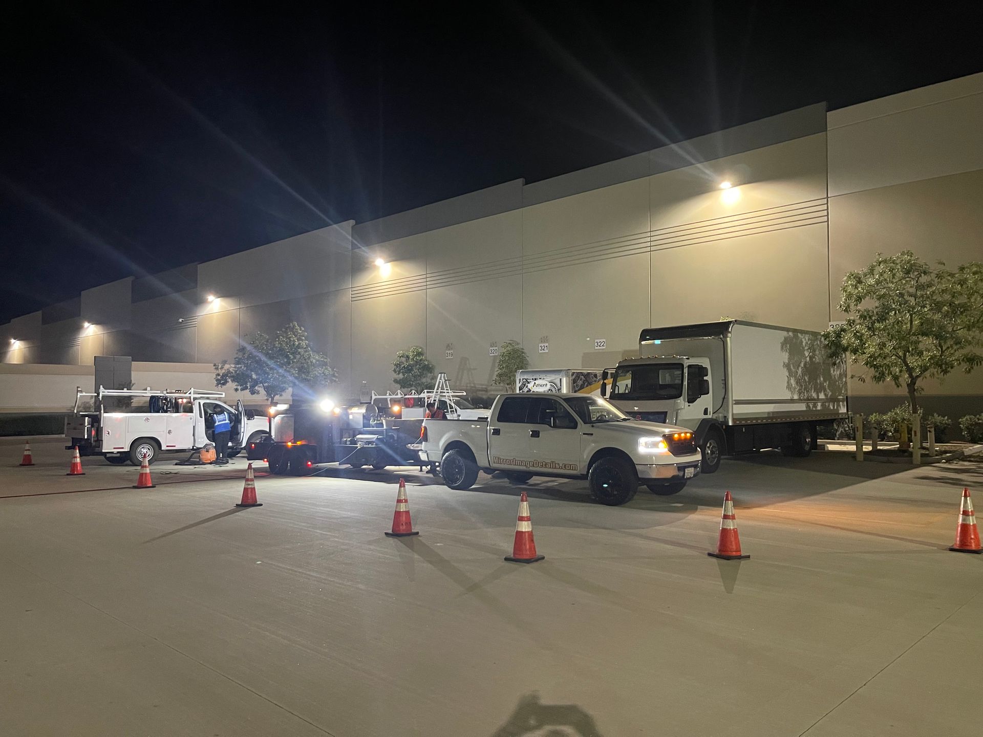 A group of trucks are parked in a parking lot at night.