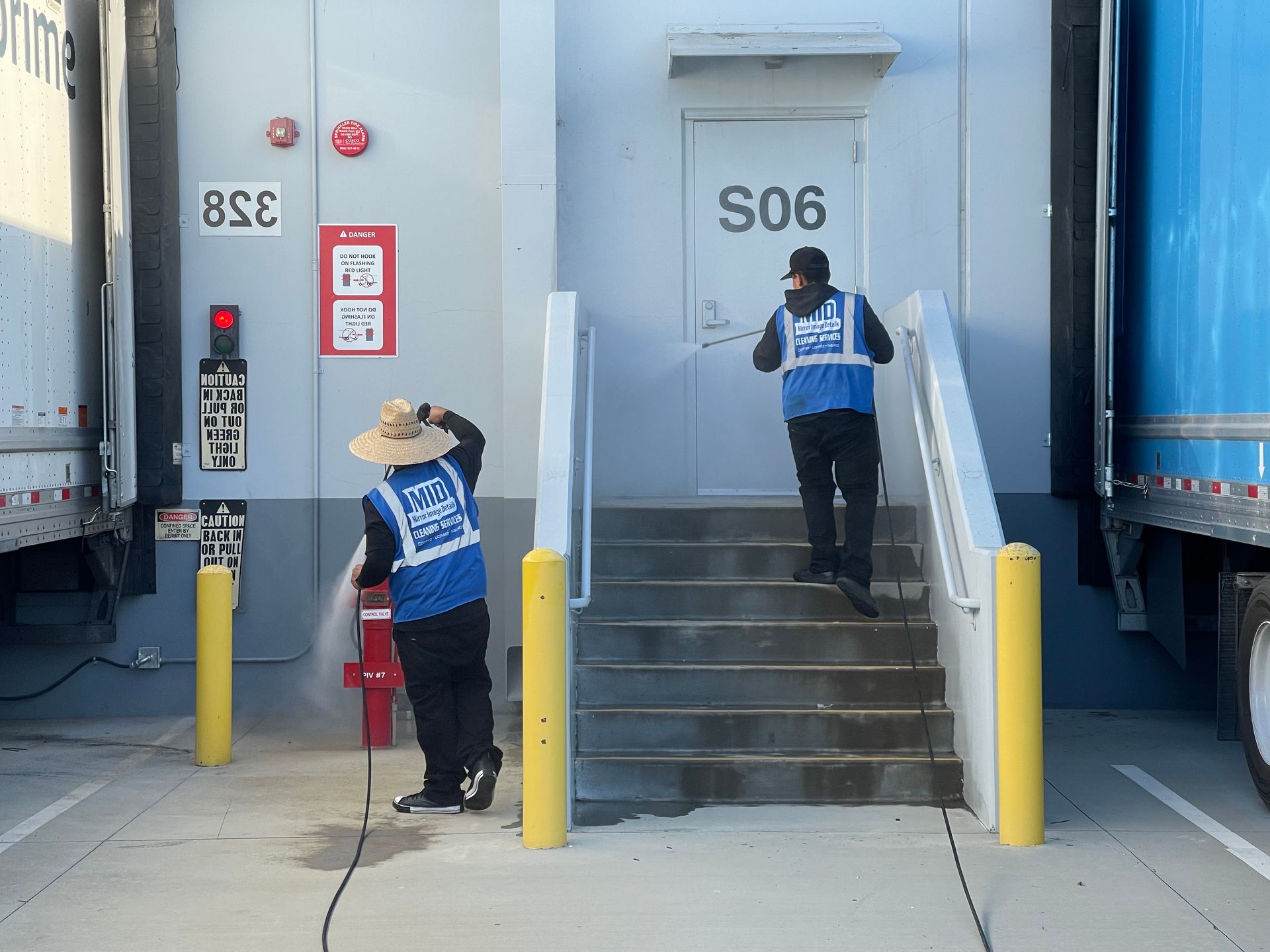 Two men are walking down stairs in front of a building with the number s06 on the door.