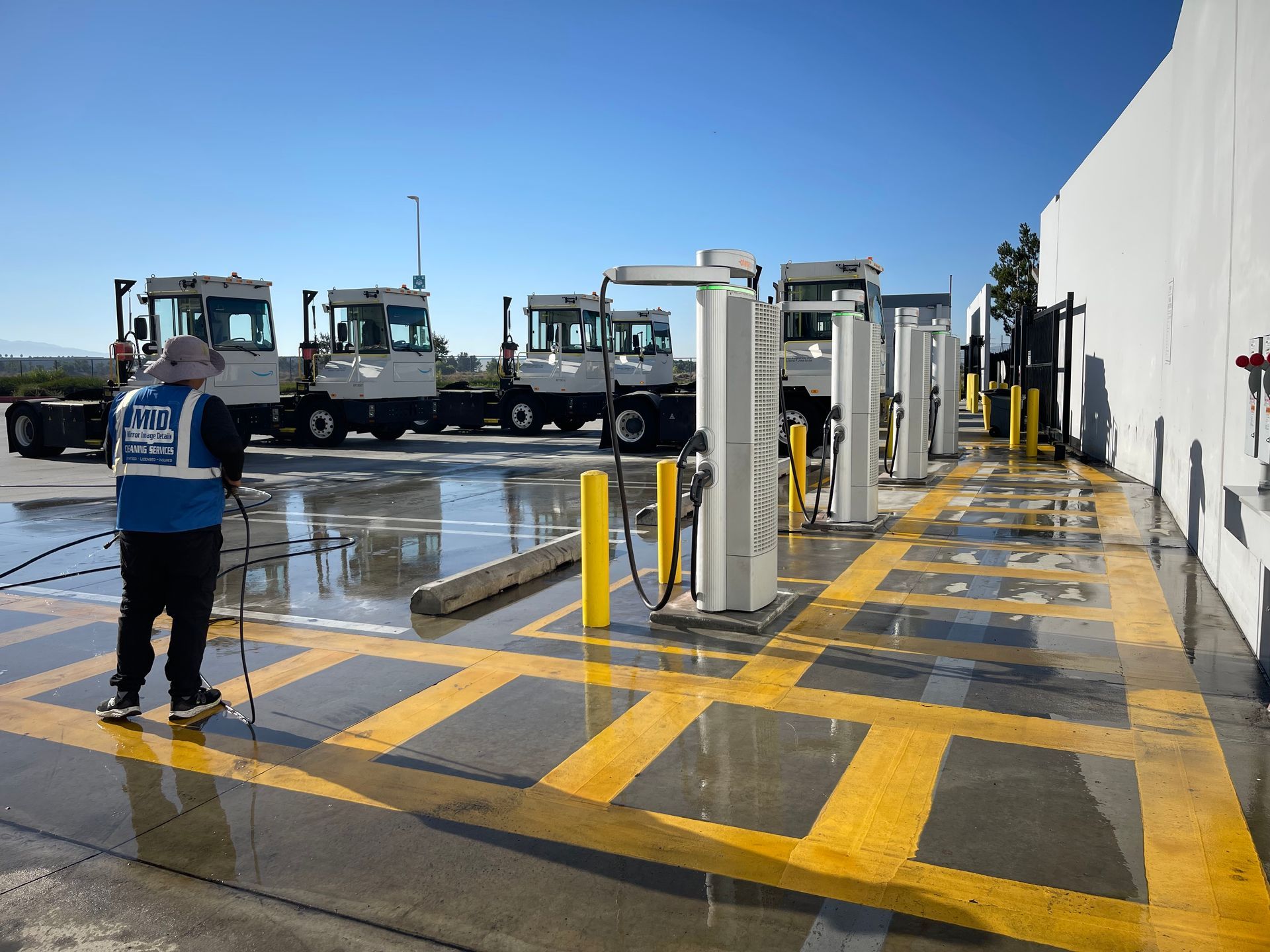 A man is standing in front of a row of trucks in a parking lot.