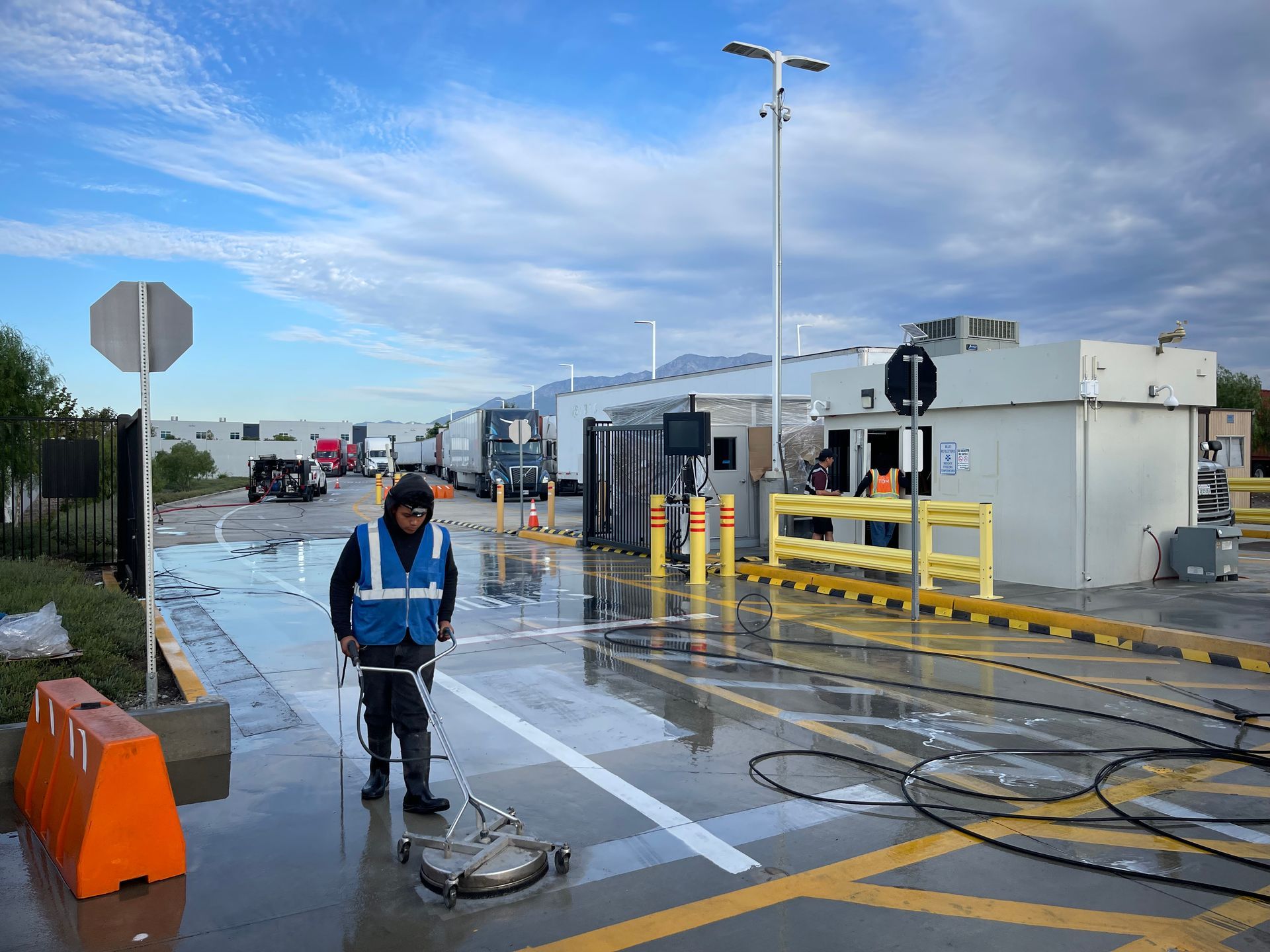 A man is cleaning a parking lot with a hose.