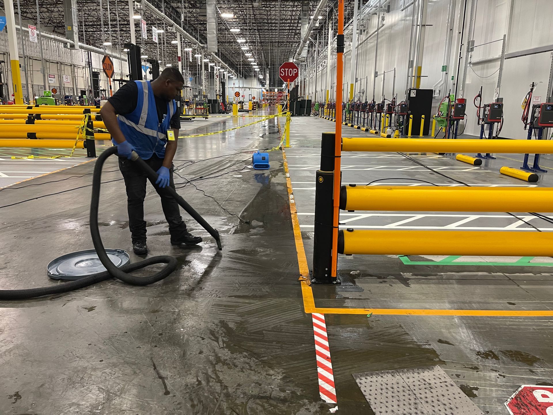 A man is using a vacuum cleaner to clean a warehouse floor.