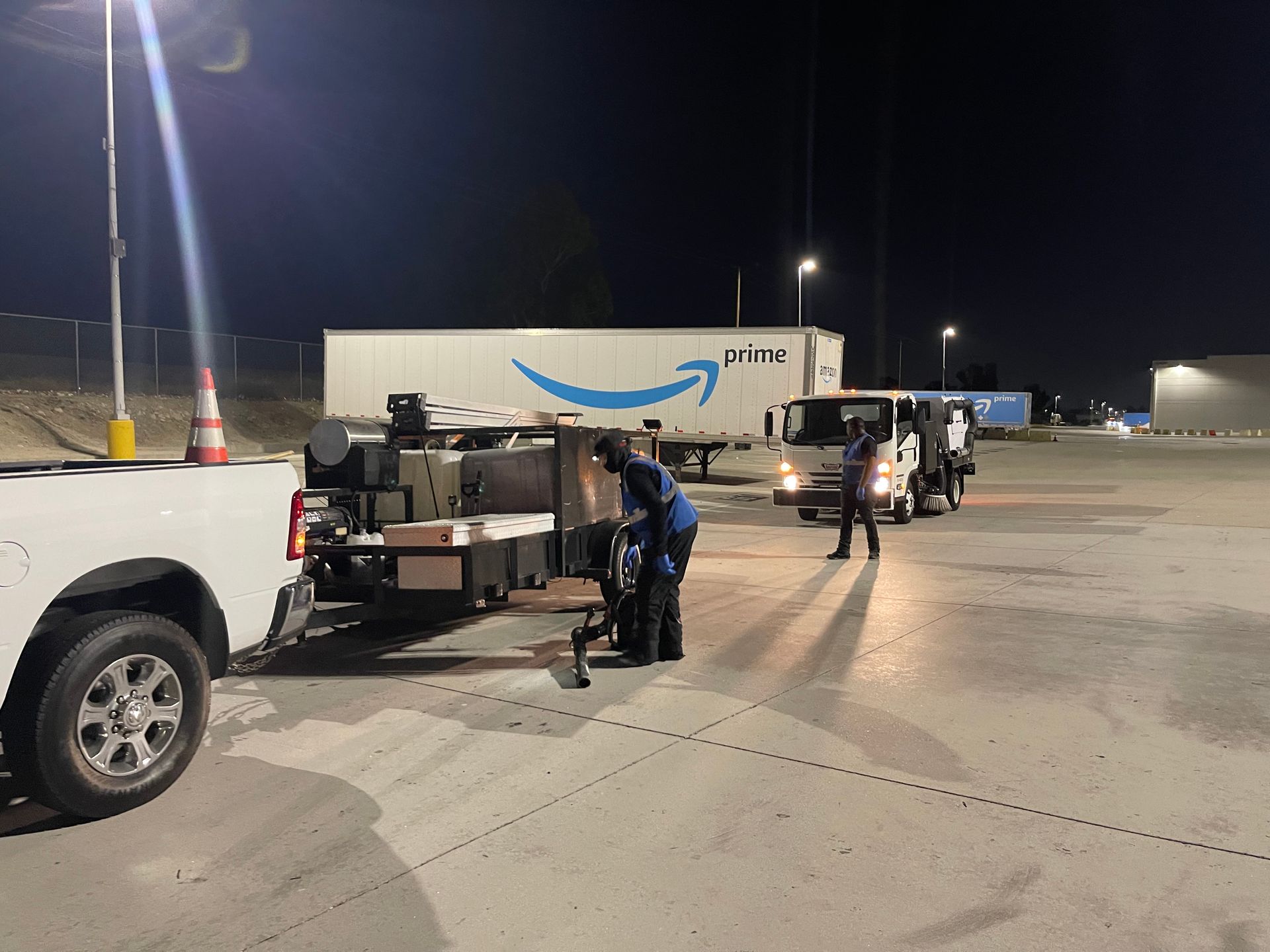 A group of trucks are parked in a parking lot at night.