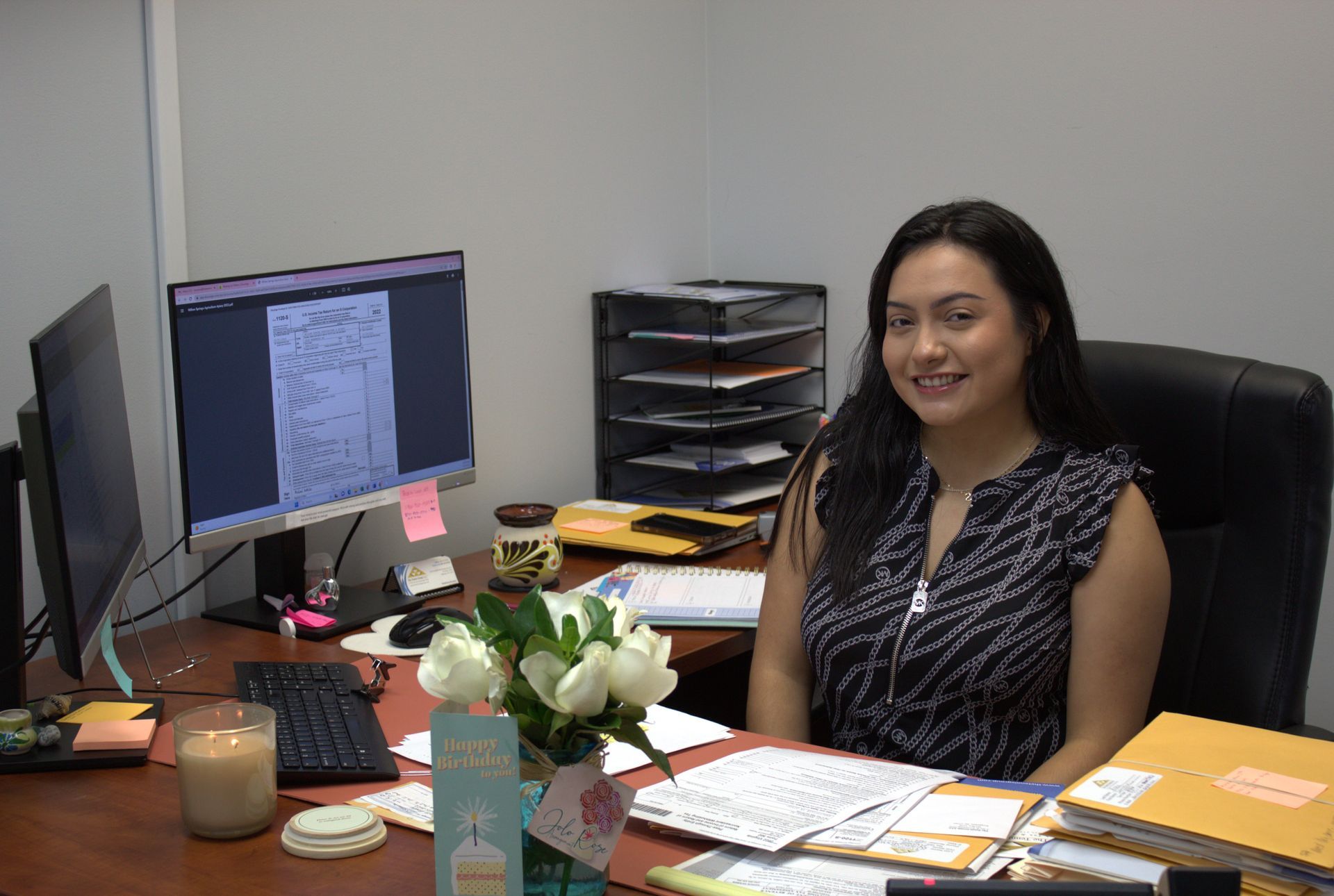 Estefania Romero, Senior Tax Analyst - Ext. 209 at The Tennie Group LLC, working at her desk in the corporate office. Supporting clients with business accounting, tax services, and financial operations.