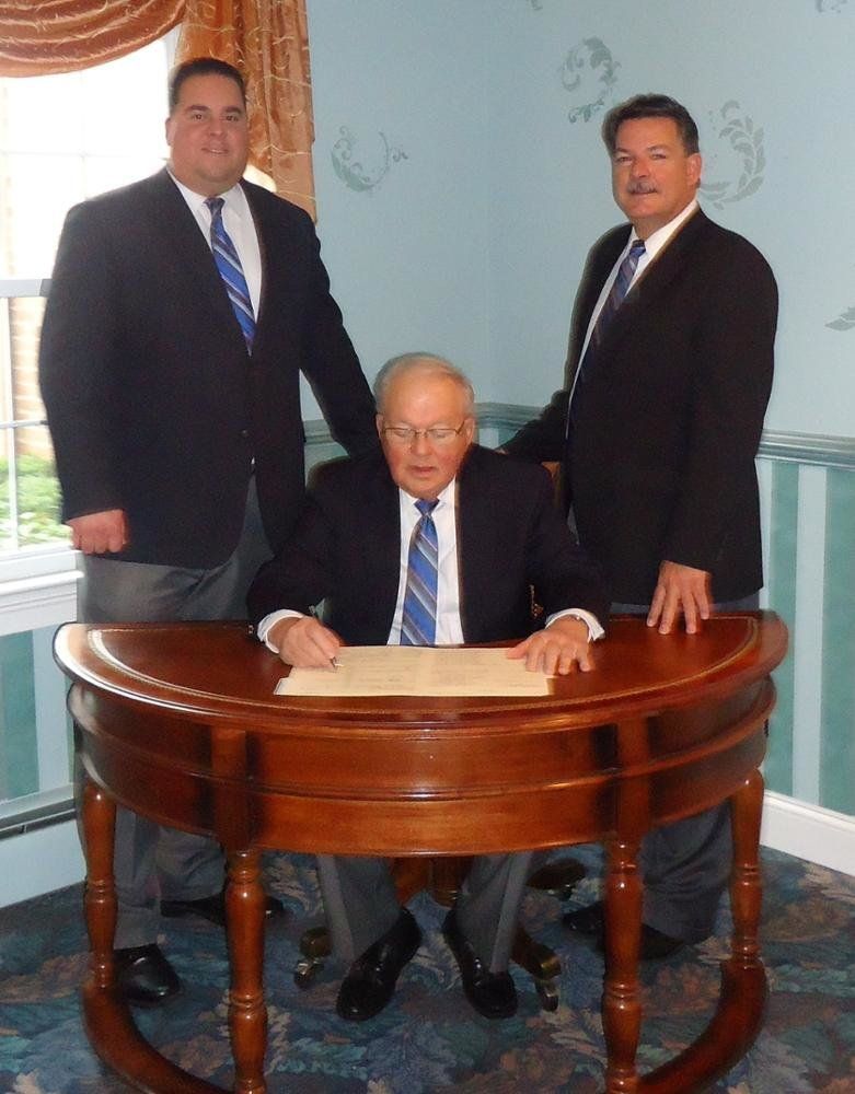 Three men in suits and ties are posing for a picture