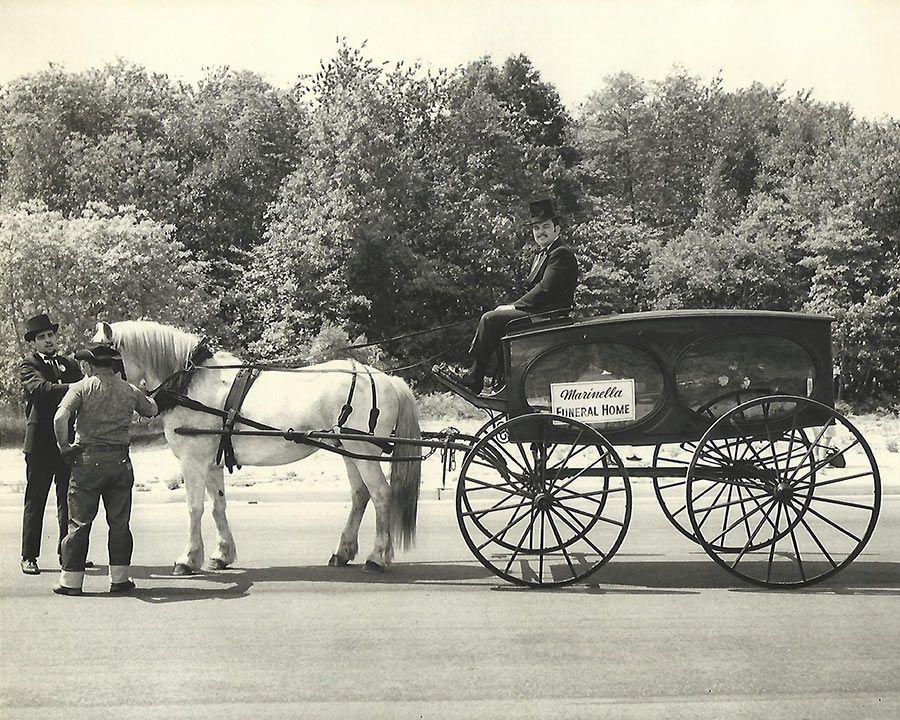 A black and white photo of a horse drawn carriage