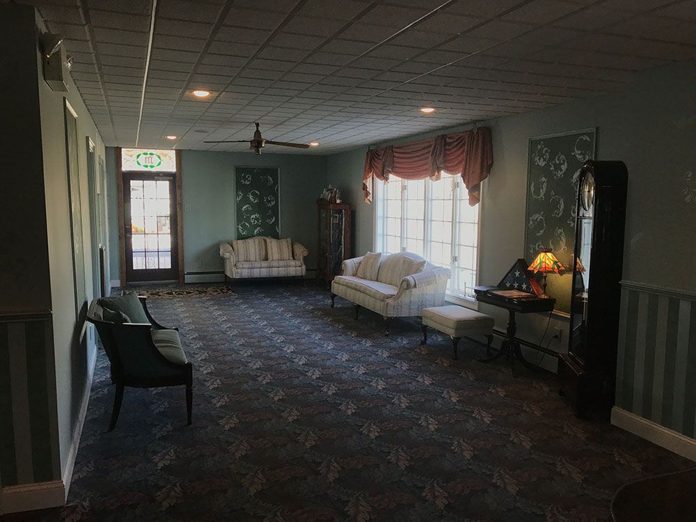 A living room with a couch , chairs , and a clock.