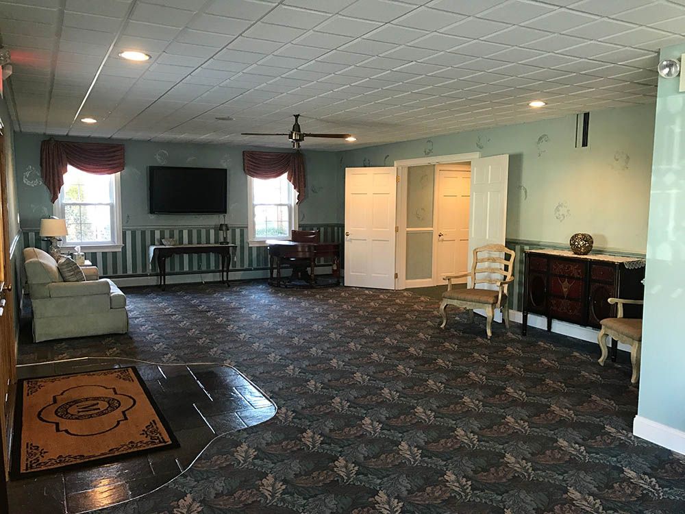 A living room with a couch , chairs , a television and a ceiling fan.