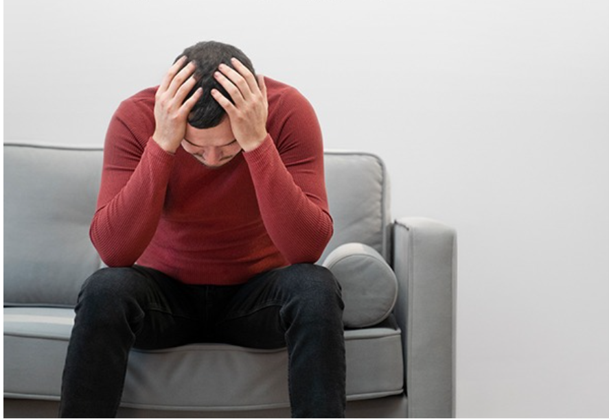 Man in a red shirt with hands on head