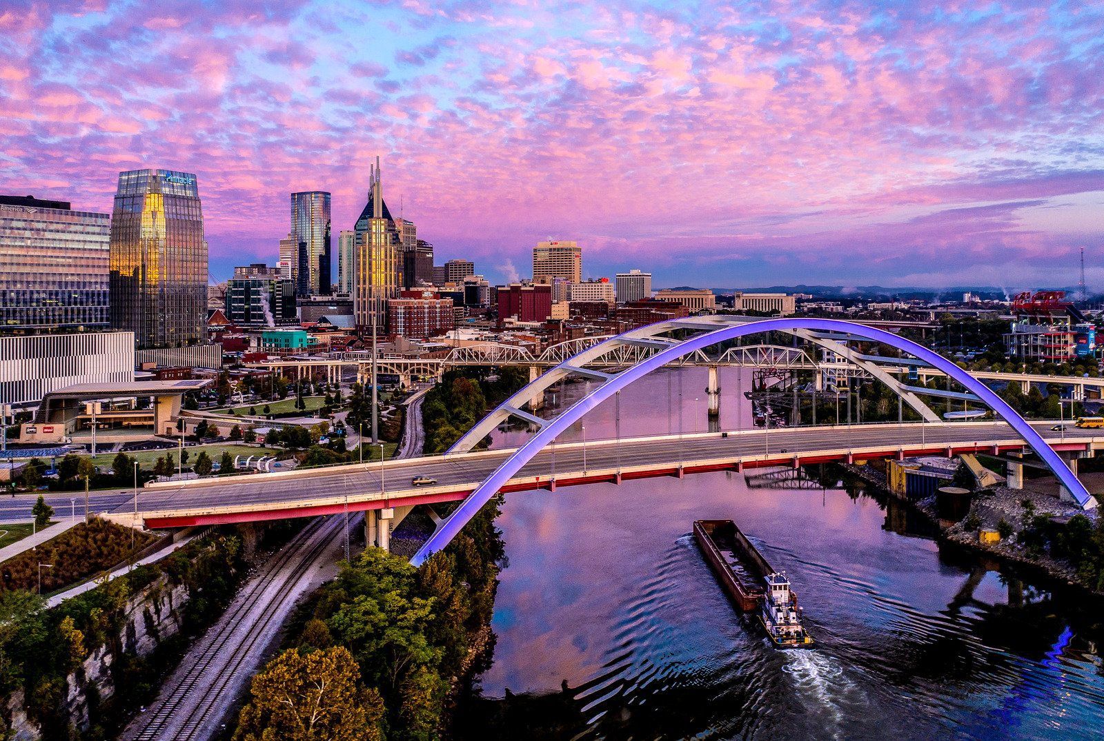 An aerial view of a bridge over a river with a city in the background.