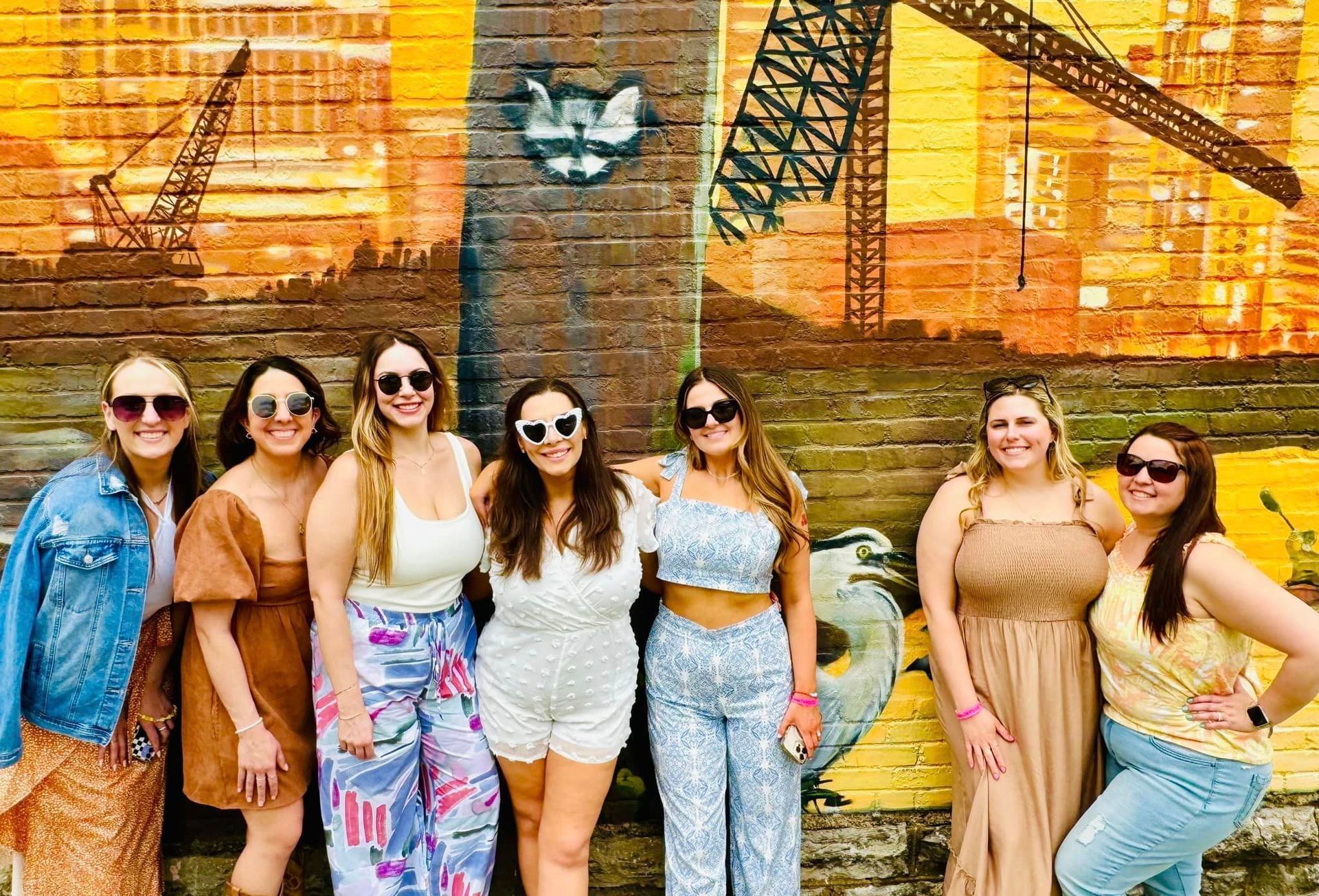 A group of women are posing for a picture in front of a brick wall.