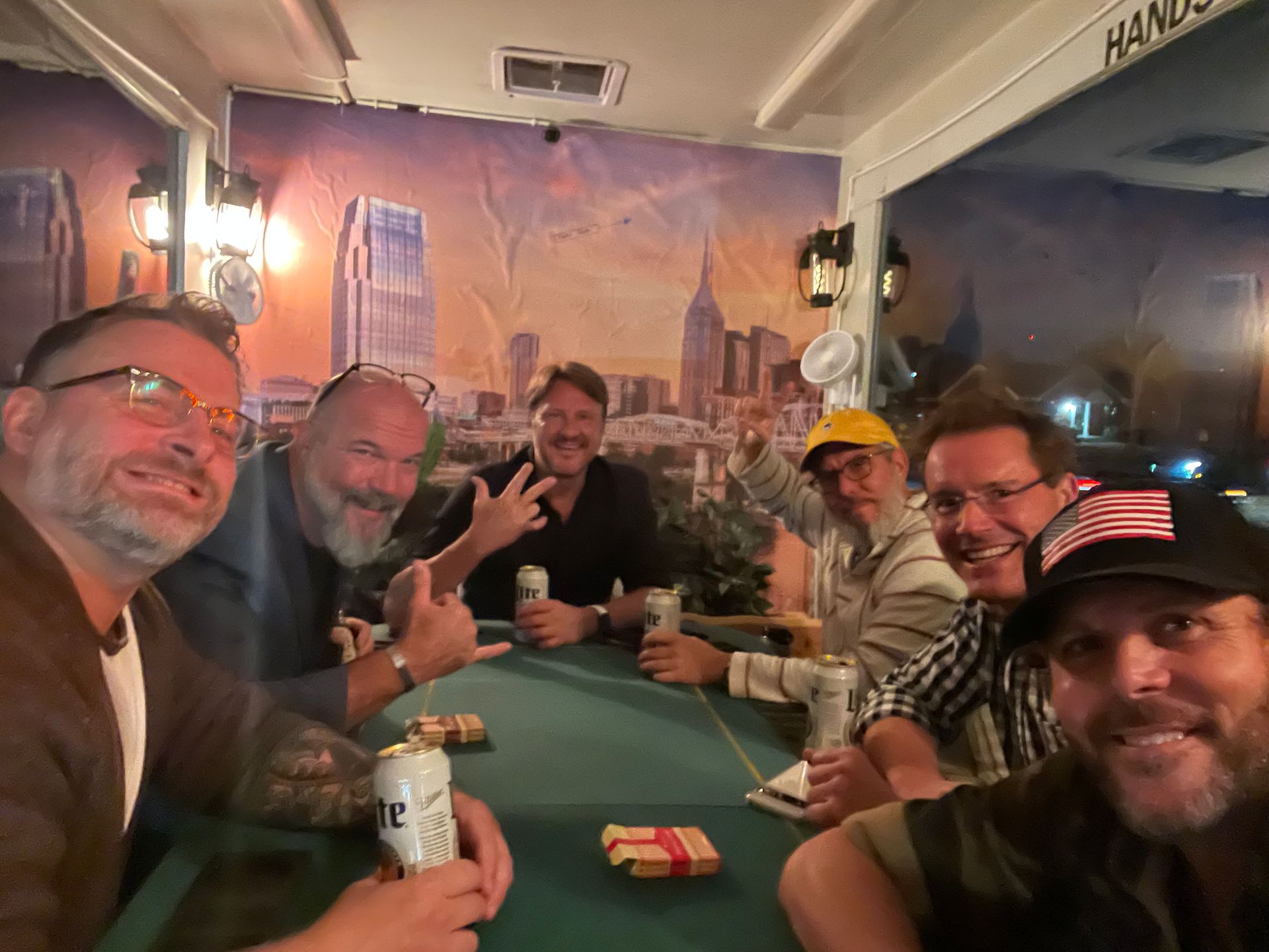 A group of men are sitting around a table drinking beer