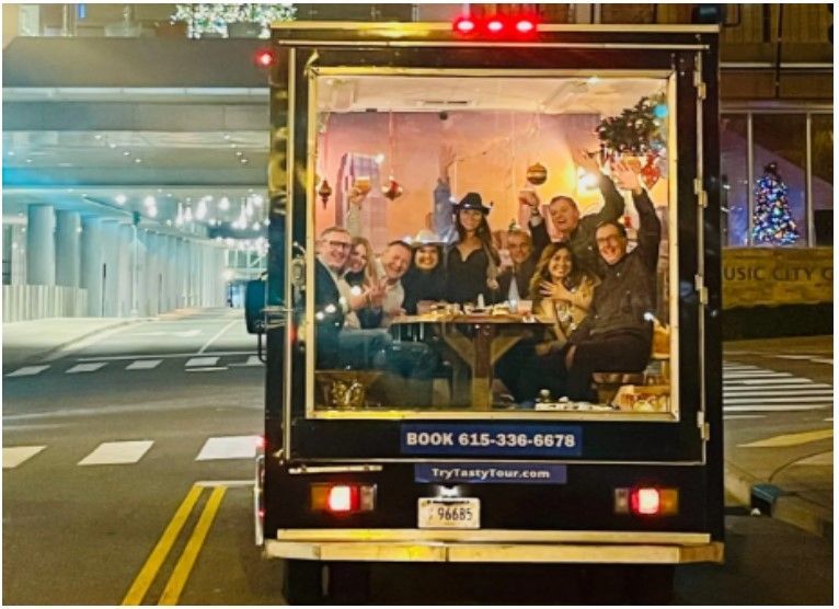 A group of people are posing for a picture in the back of a food truck