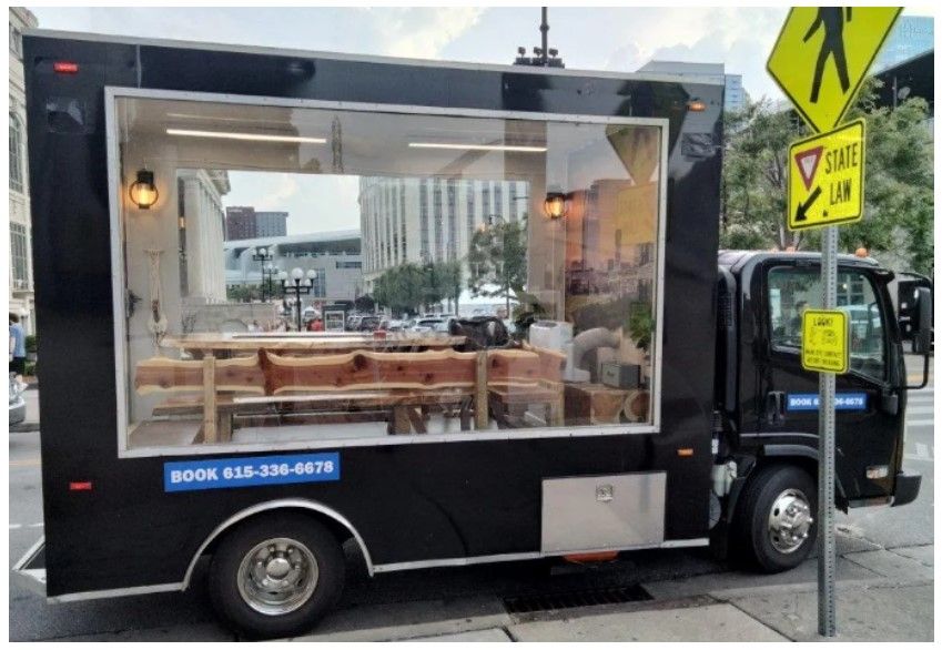 A black food truck is parked on the side of the road