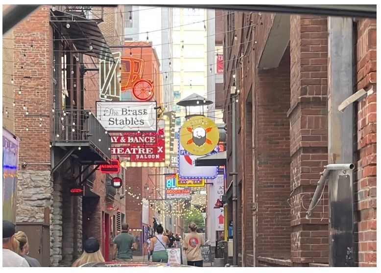 A narrow alleyway with a sign that says ' the house stables ' on it