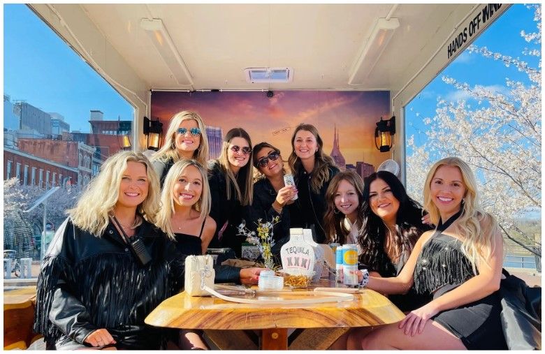 A group of women are posing for a picture while sitting at a table.