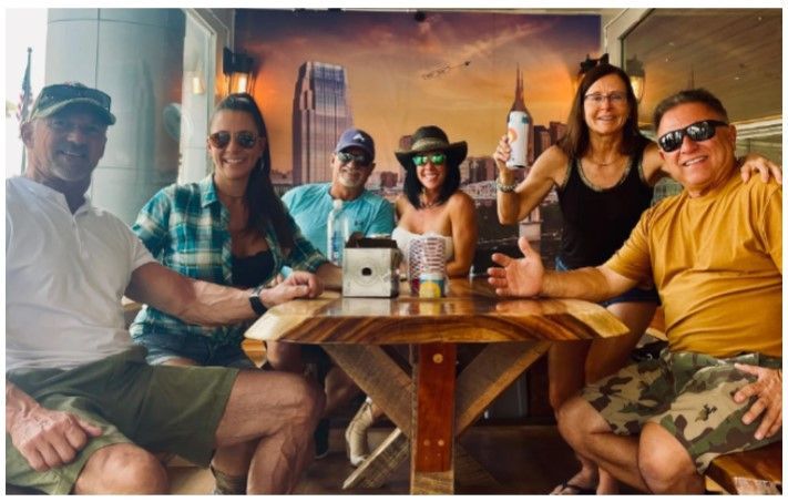 A group of people are sitting around a table with a city in the background.