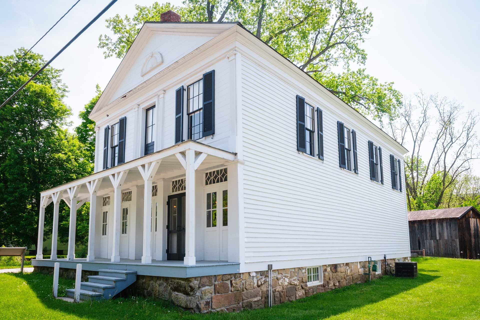 A large white house with black shutters and a porch