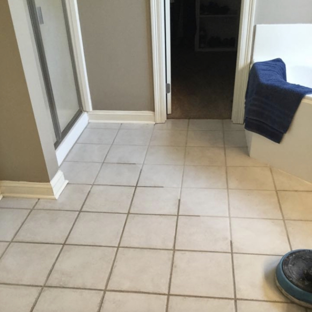 A bathroom with white tiles and a blue towel on the bathtub.