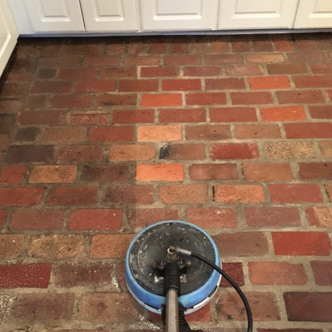 A vacuum cleaner is sitting on a brick floor.