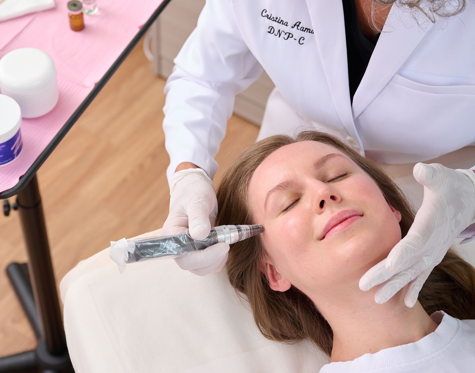 A woman is getting a microneedling treatment from a nurse practitioner