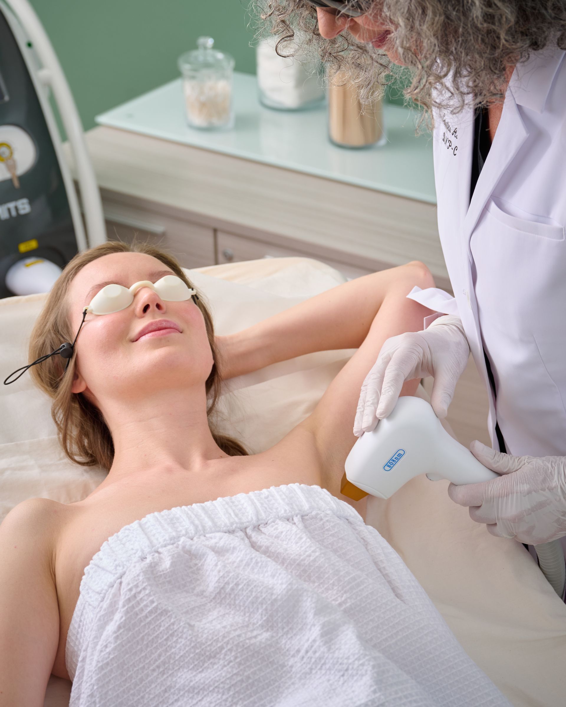 A woman is getting a laser hair removal treatment on her armpit.