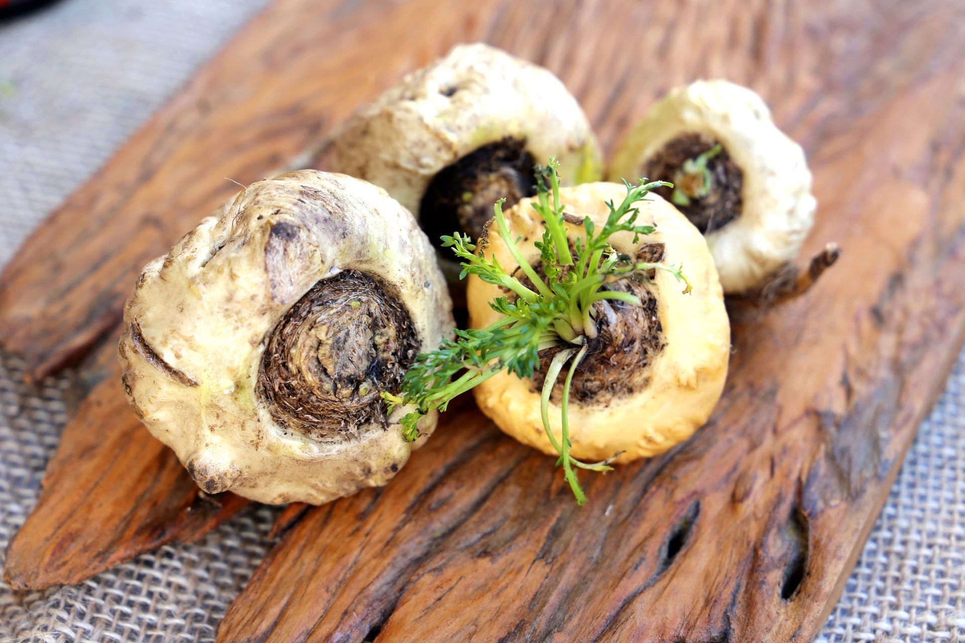 Three maca root vegetables are sitting on a wooden cutting board.