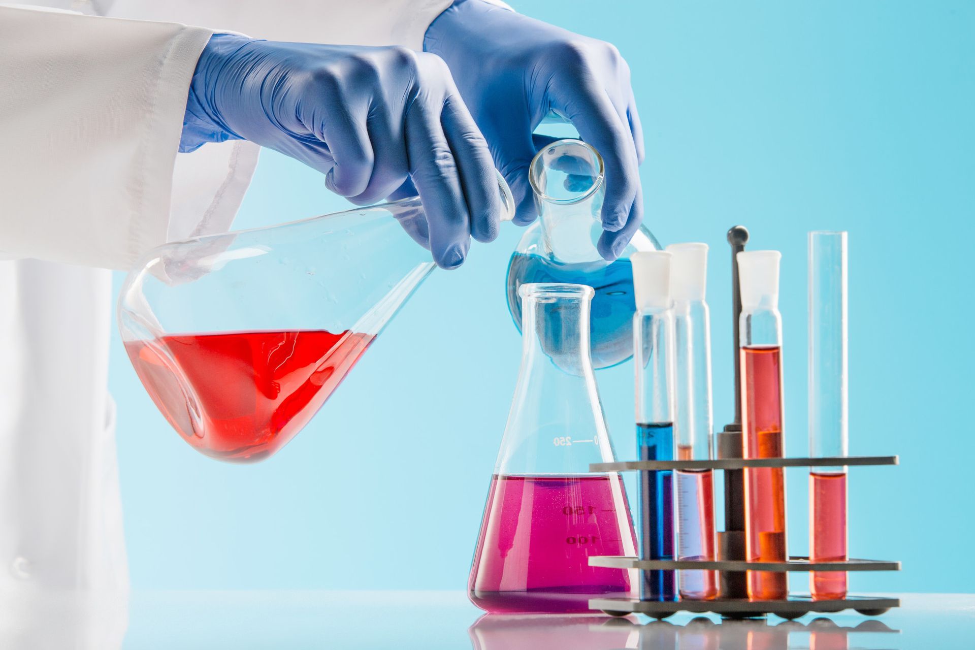 A scientist is pouring a red liquid into a beaker.