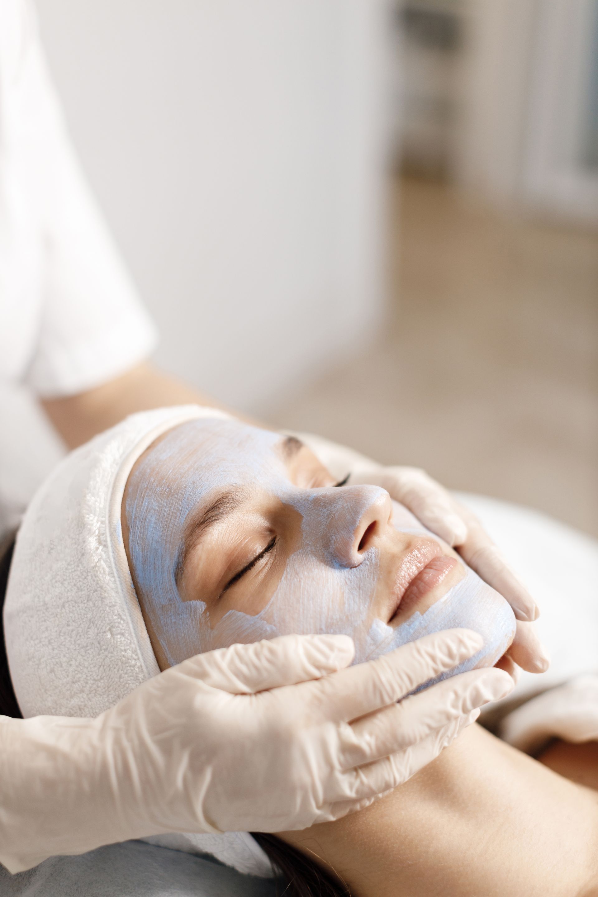 A woman is getting a facial treatment with a blue mask on her face.