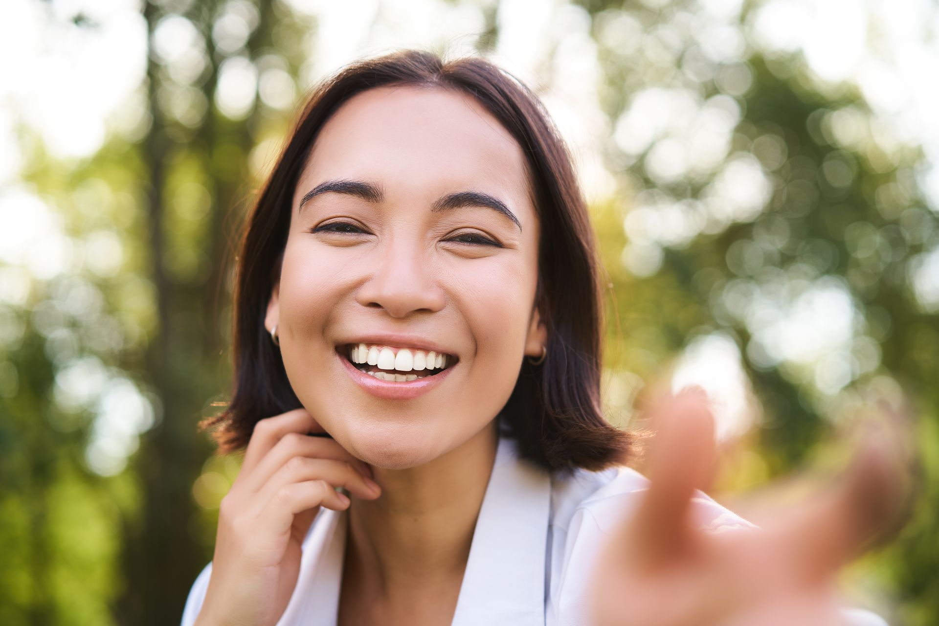 A woman is smiling and pointing at the camera.