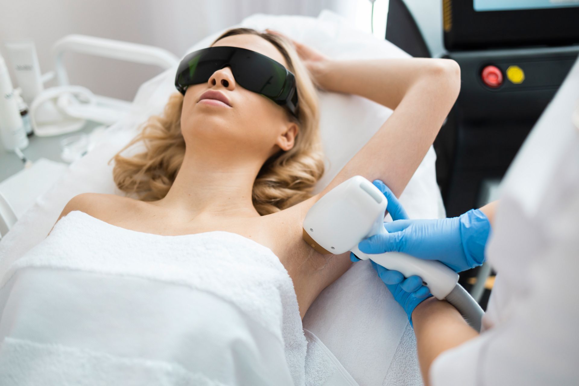 A woman is getting a laser hair removal treatment on her armpit.