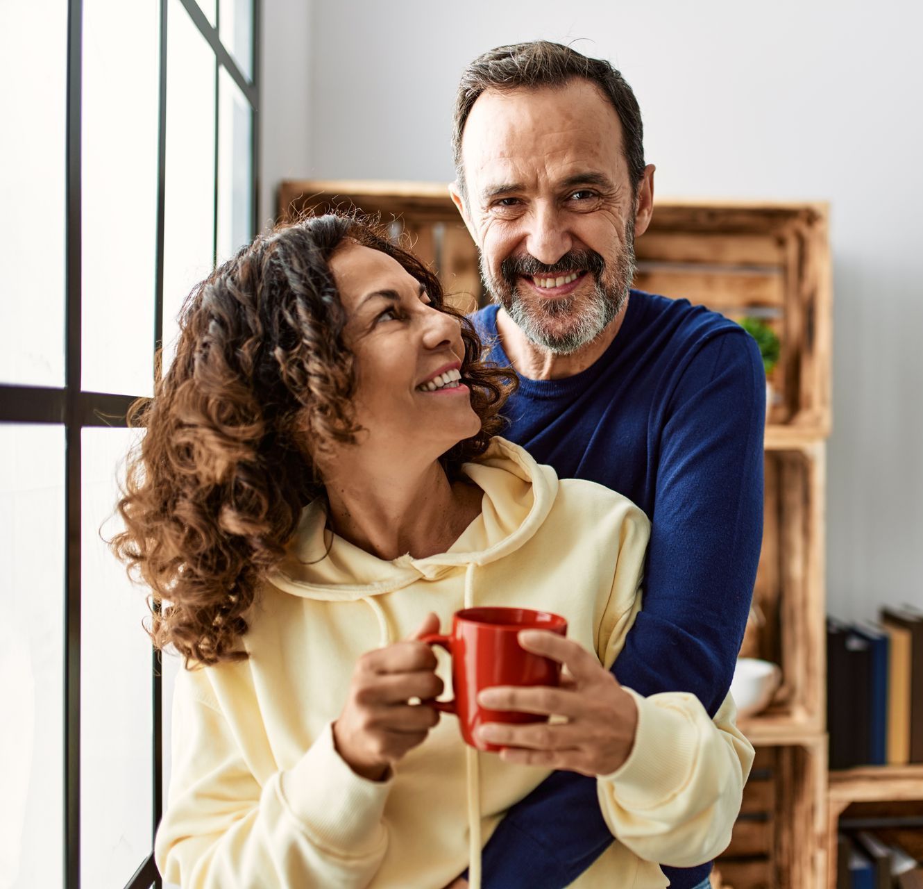 A man is hugging a woman who is holding a cup of coffee.