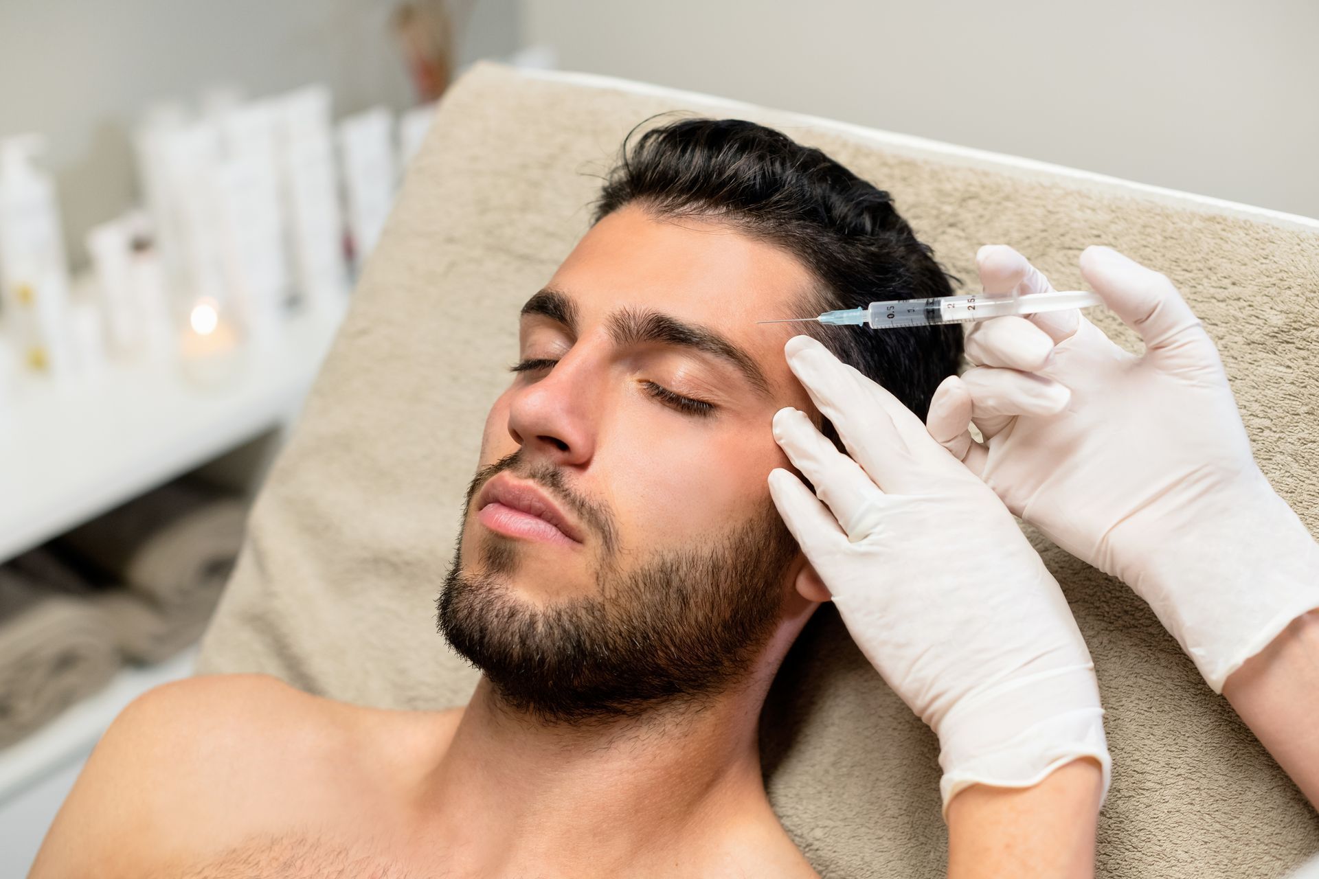 A man is getting an injection in his forehead in a beauty salon.