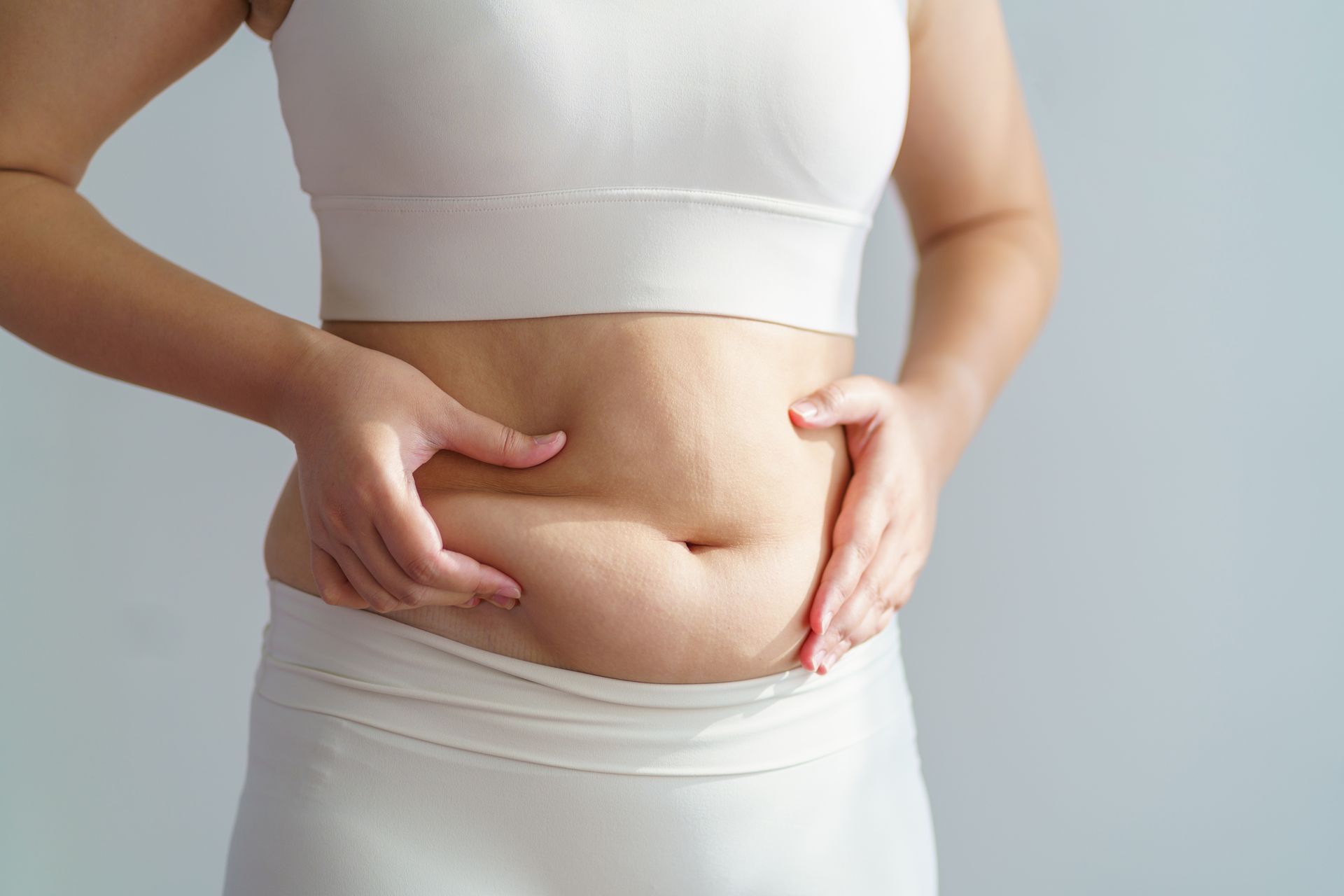 A woman is holding her stomach with her hands.