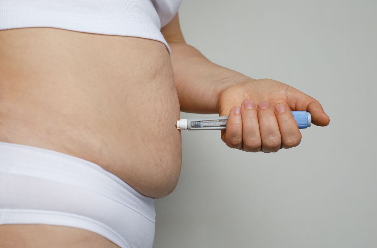 A woman is injecting herself with an insulin pen.