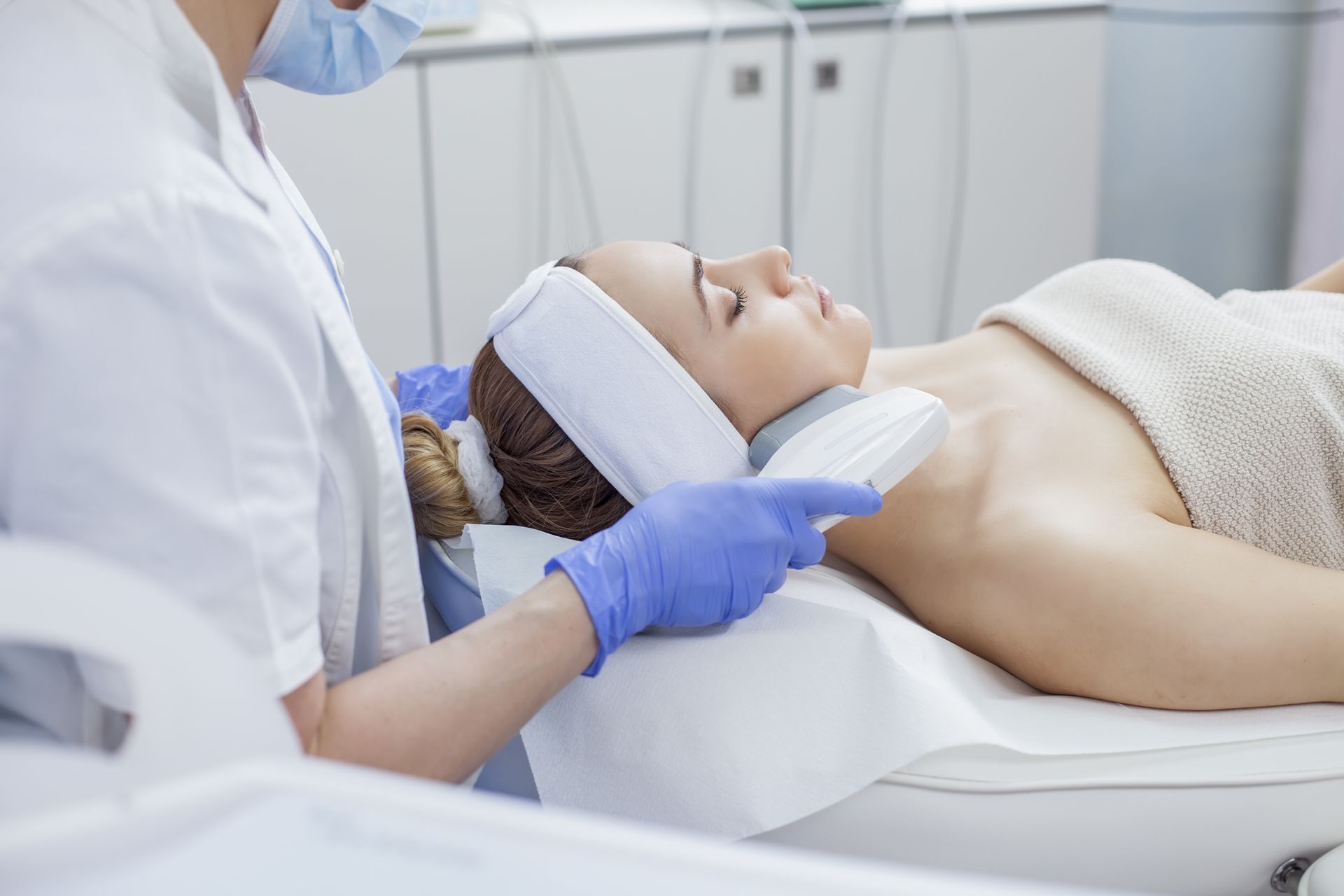 A woman is getting a laser treatment on her armpit in a beauty salon.