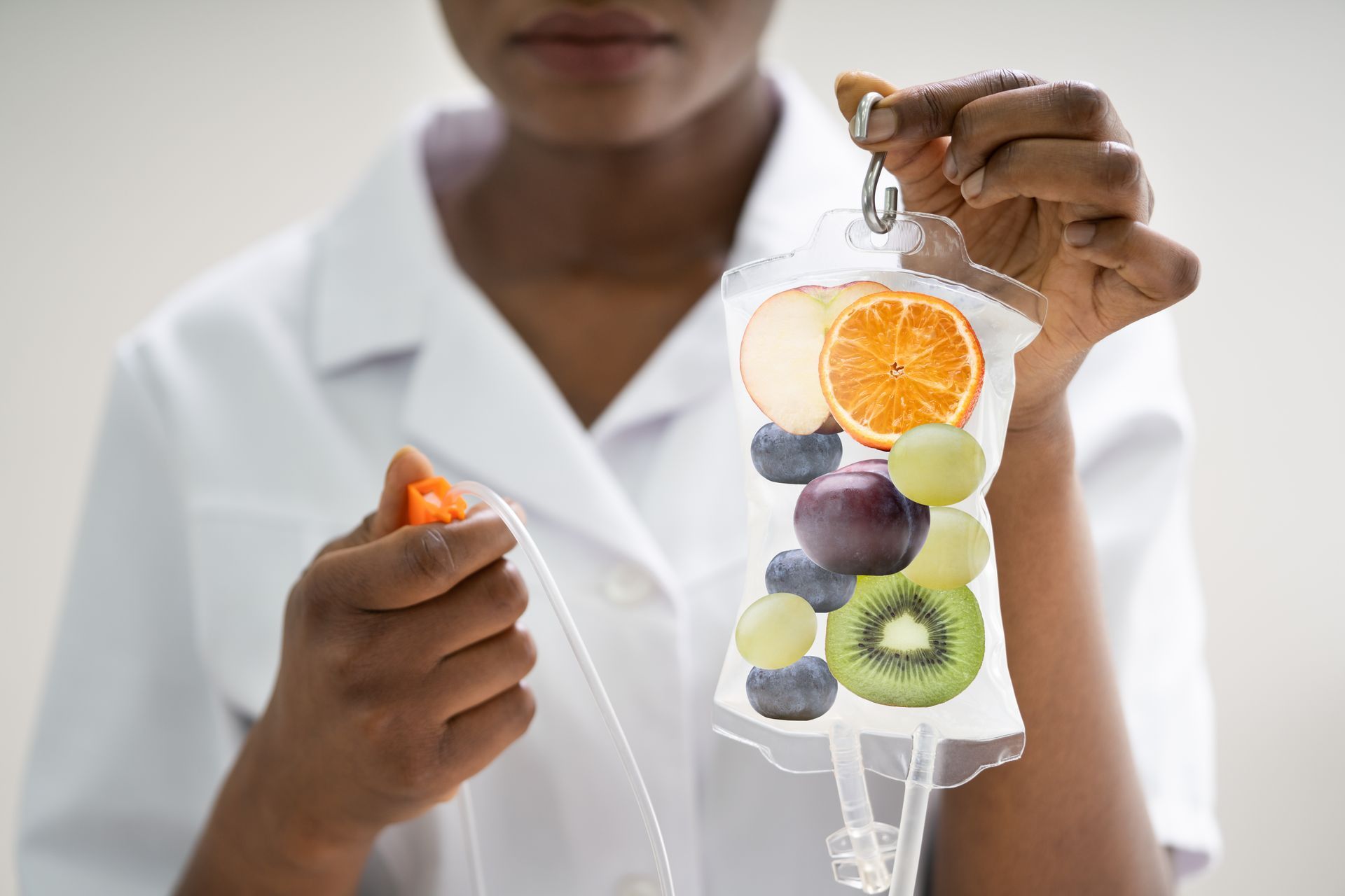 A nurse is holding a bag of fruit in her hand.