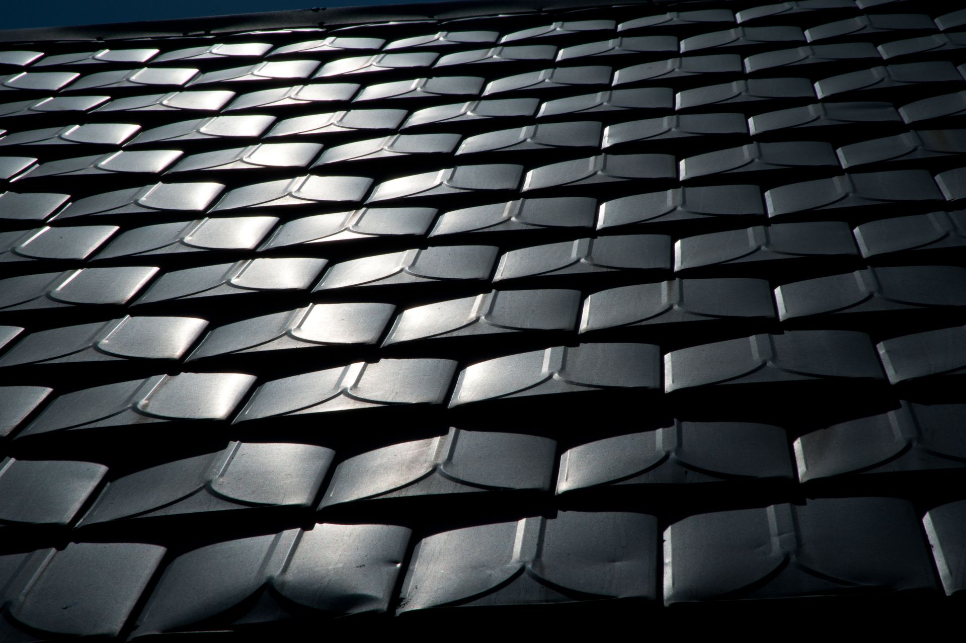 Close-up of a black metal roof with overlapping, curved panels.