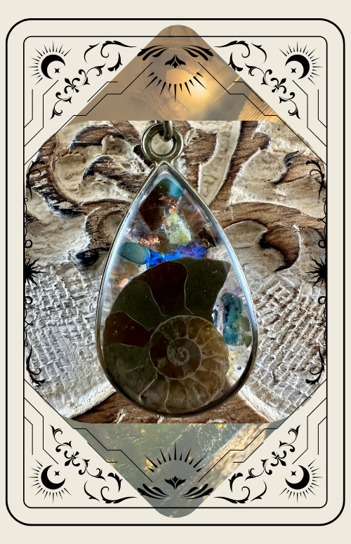 Pendant with ammonite fossil and gemstones set against a decorative background, within a tarot card frame.