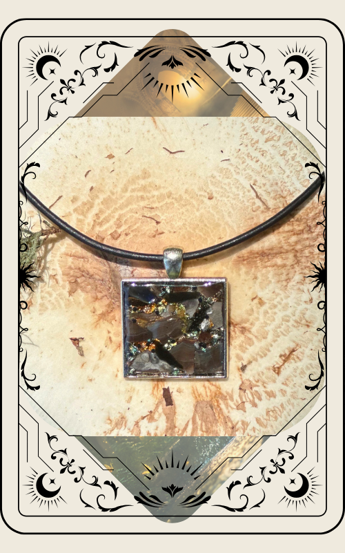 Square pendant necklace with dark, sparkly, and iridescent pieces encased in clear resin.