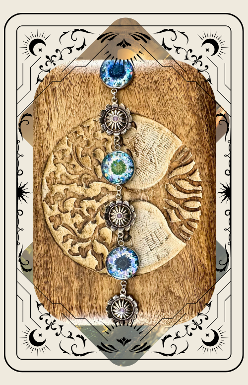 A blue, shimmering resin bead set in a metal chain with western-style floral embellishments against a wood background.