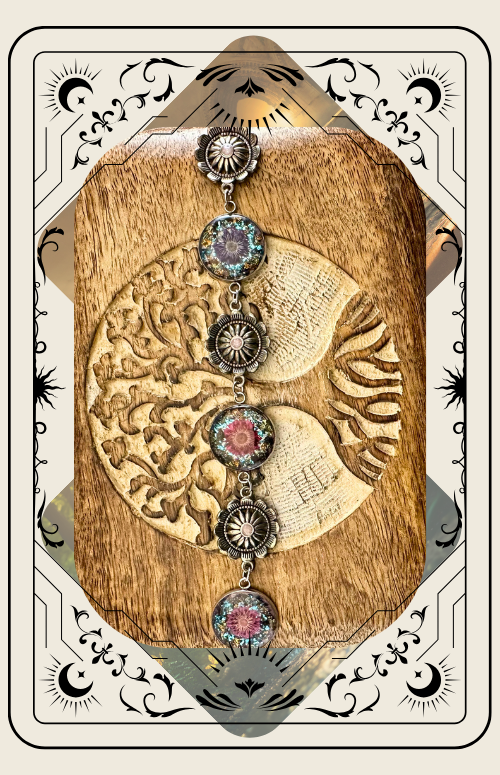 A close-up of a bracelet with a colorful, glittery circular centerpiece, framed by a decorative tarot-style border.
