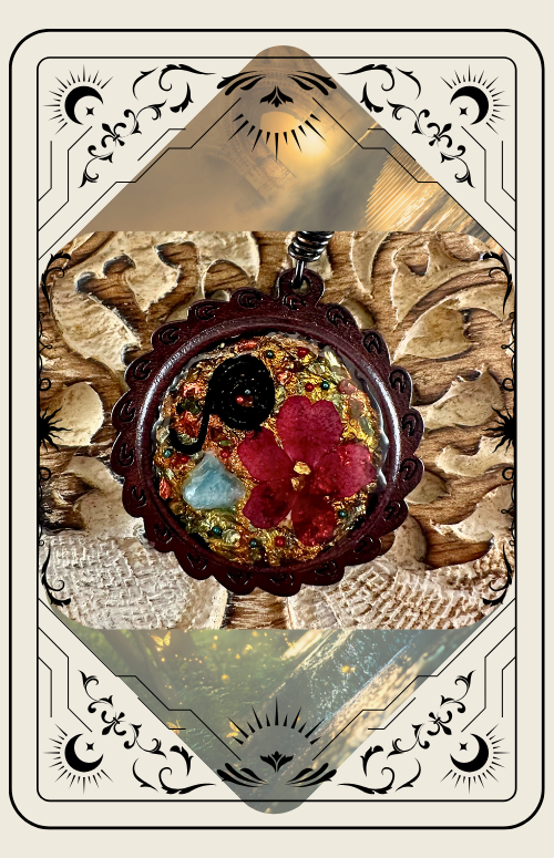 Pendant with red flower and black spiral in resin, surrounded by glitter, set against a carved wooden surface.