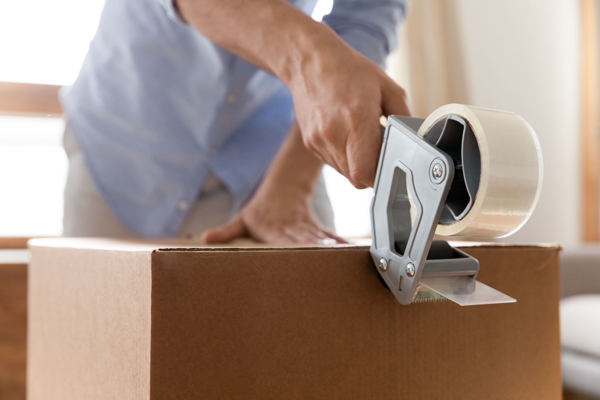 A cardboard box with a tape dispenser on top of it.