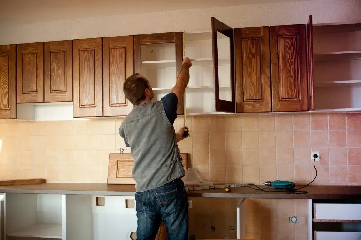 Carpenter installing wooden kitchen cabinets.