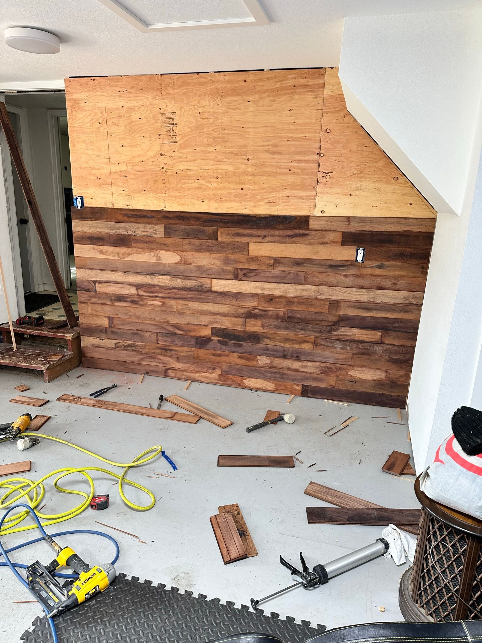A room with a wooden wall and a lot of tools on the floor.