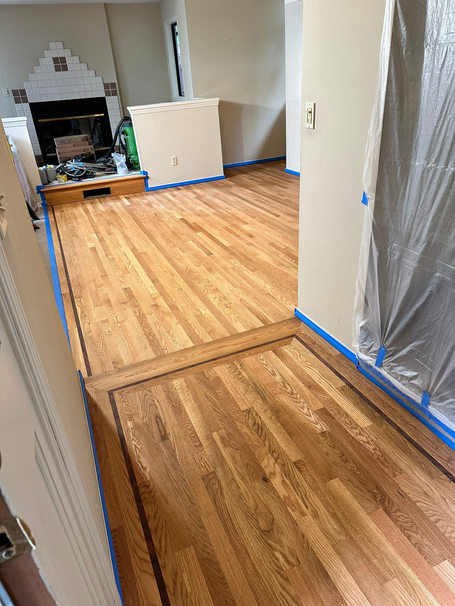 A wooden floor is being painted in a living room.