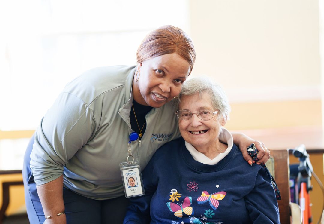 A nurse is standing next to an elderly woman in a wheelchair.